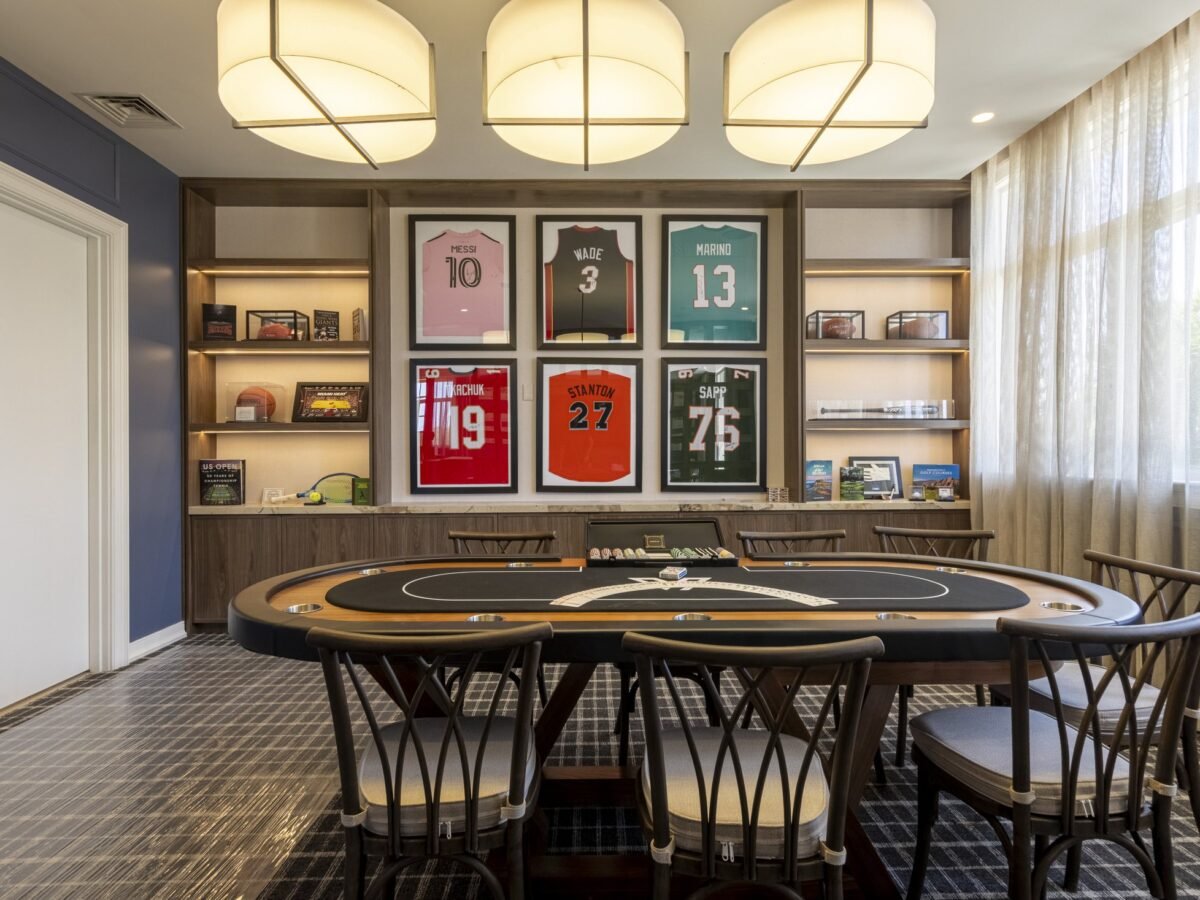 Card room with navy wallcovering and framed sports jerseys at a private golf club in Miami by Salt Wallcovering