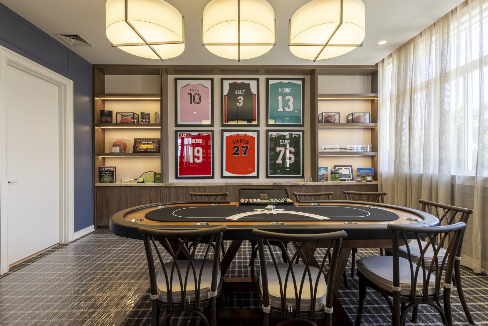 Card room with navy wallcovering and framed sports jerseys at a private golf club in Miami by Salt Wallcovering