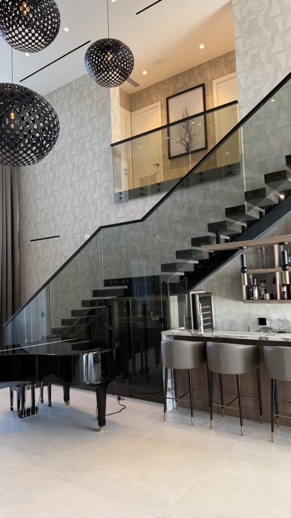 Double-height staircase and bar wall with textured wallcovering in a Miami residence by Salt Wallcovering