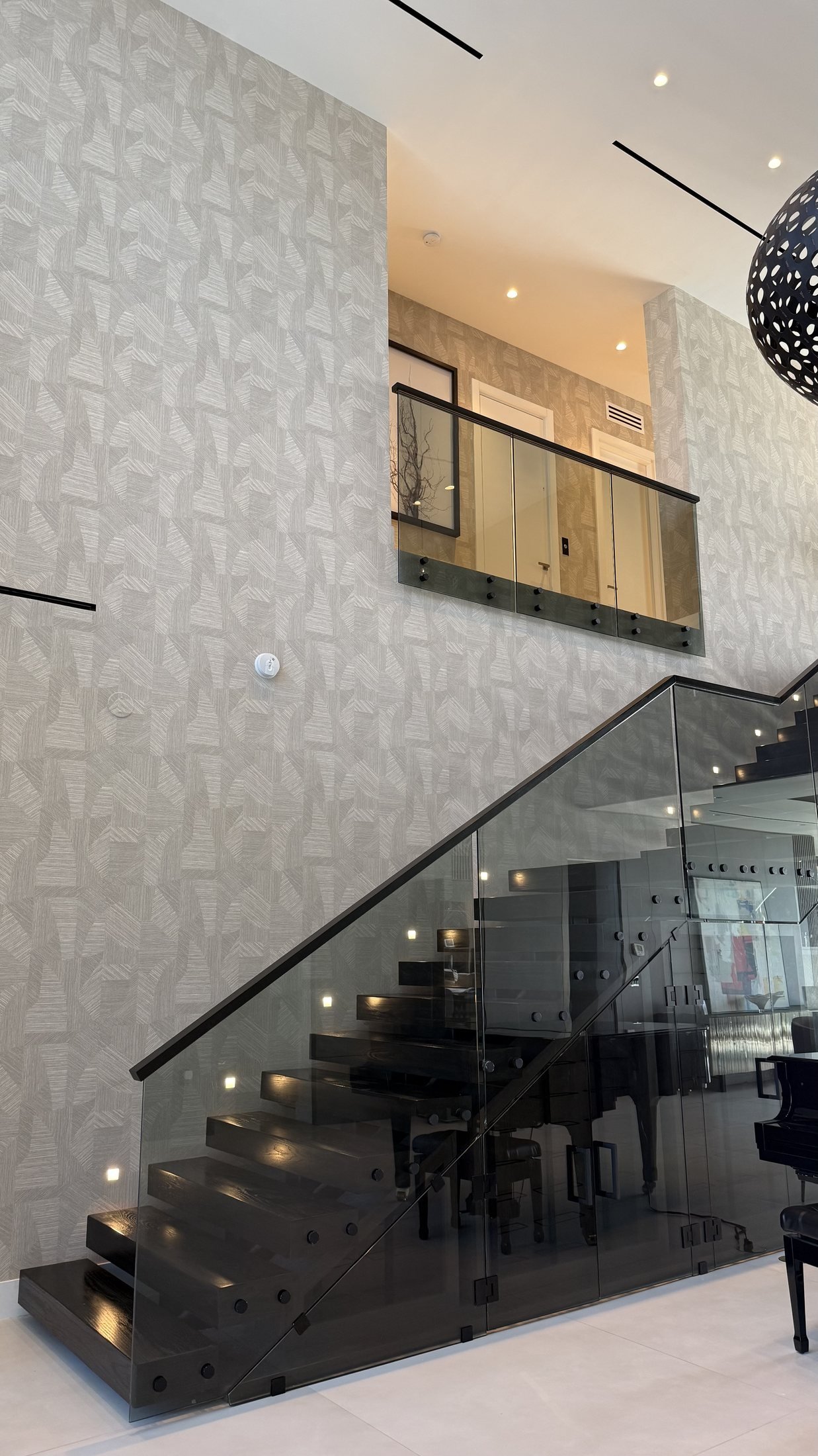 Double-height staircase wall with textured wallcovering in a Miami residence by Salt Wallcovering